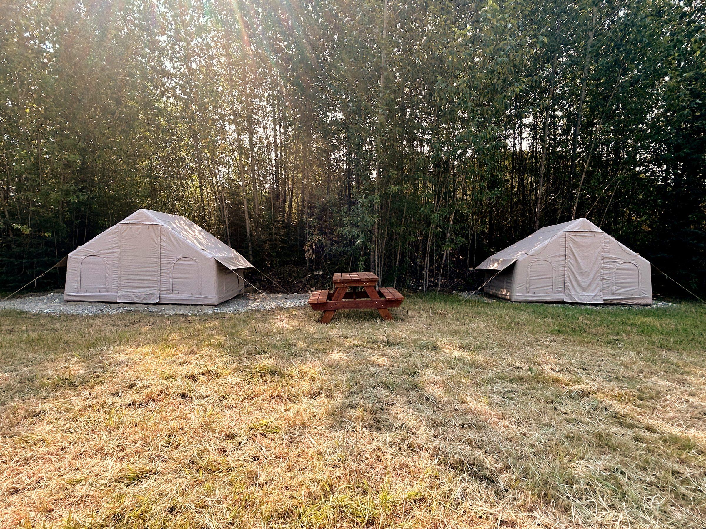 Two pre-set glamping tents beside a picnic table